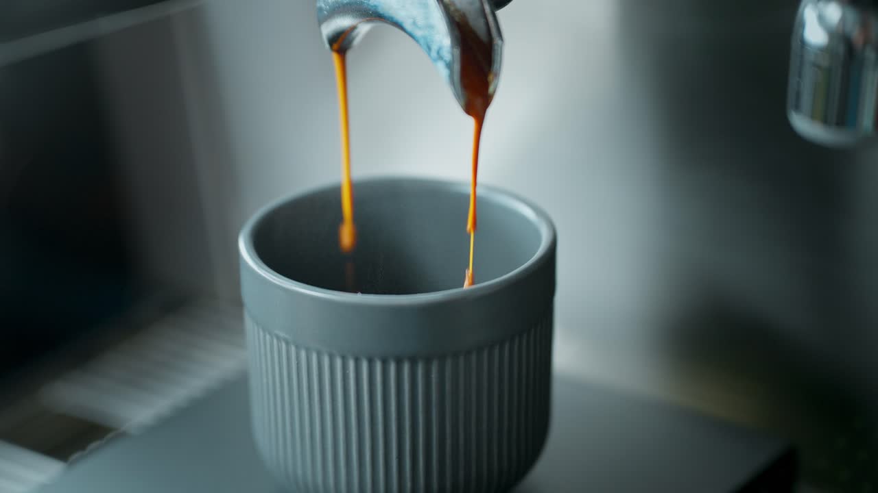 Primo piano di caffè espresso che si versa in una tazza grigia