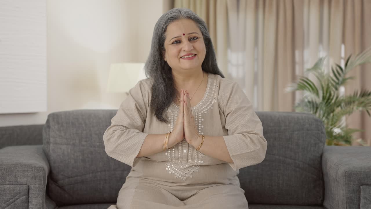 Glückliche indische ältere Frau grüßt mit Namaste.