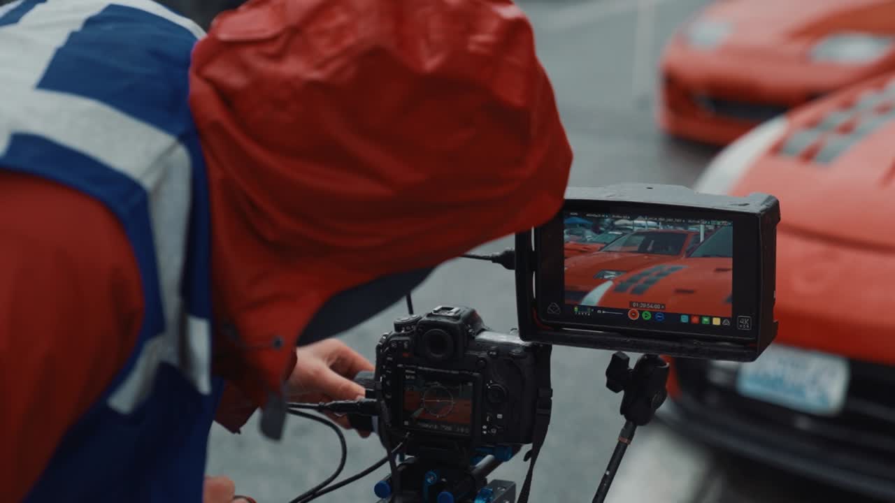 primer plano de un hombre de cámara con chaleco protector filmando un coche deportivo en un salón de automóviles