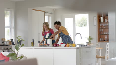 Happy-diverse-couple-cooking-and-throwing-waste-out-in-kitchen,-slow-motion