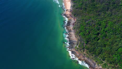 aerial view of foamy waves breaking on the rocky shore at noosa national park near noosa heads in queensland, australia