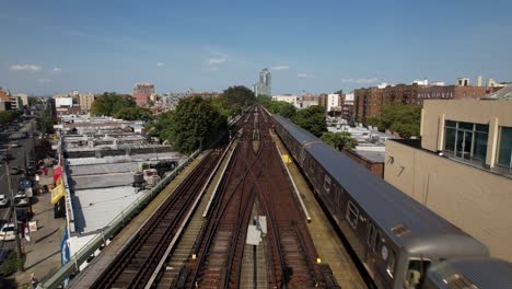 an aerial view of train tracks with a train travelling away from the camera on a sunny day