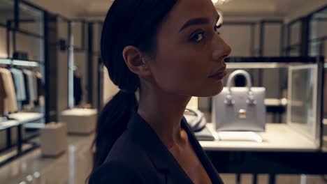 side view of a sophisticated woman appreciating designer handbags displayed in a brightly lit, upscale boutique, showcasing a moment of luxury shopping