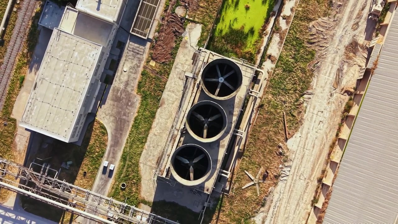 View of industrial cooling towers and facility from above showing cooling system, energy efficiency efforts, and surrounding landscape
