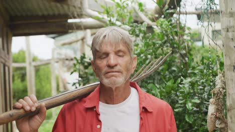 Portrait-of-senior-caucasian-man-walking-with-fork-in-garden