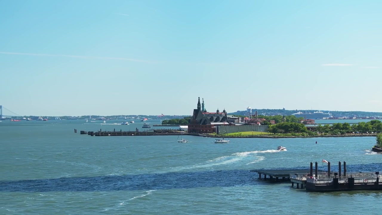 Panoramica aerea media che inquadra Ellis Island e la Statua della Libertà sull'East River.