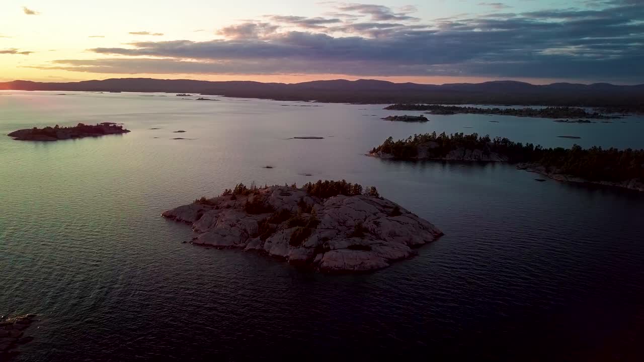 석양 푸른 호수에 푸른 소나무가 있는 바위 화강암 섬, 드론 공중 넓은 돌리