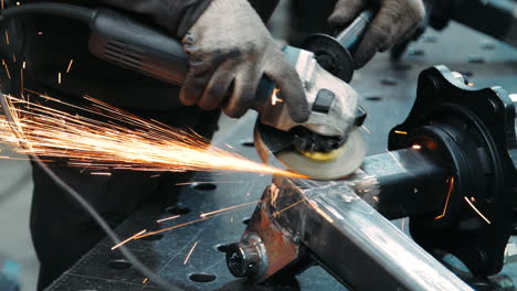 professional worker polishing metal surface with electric grinder in workshop