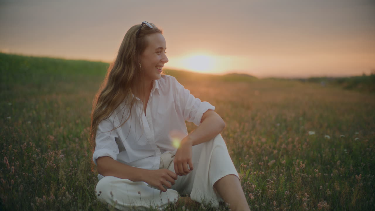 황혼에 초원에서 미소 짓는 여자