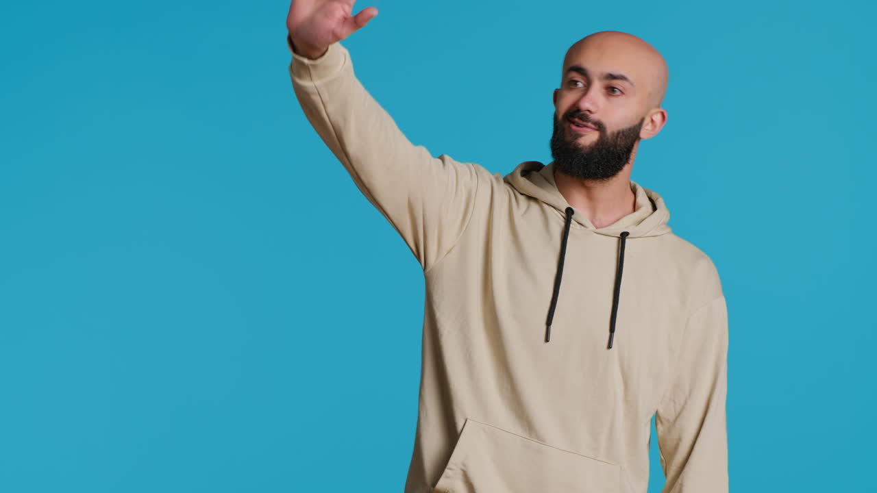 un tipo del medio oriente da la bienvenida a la gente en el estudio con una ola.