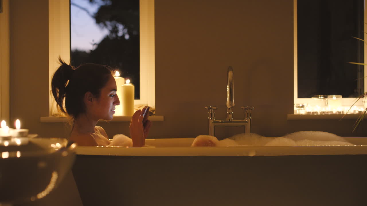 женщина расслабляется в пузырьковой ванне с телефоном