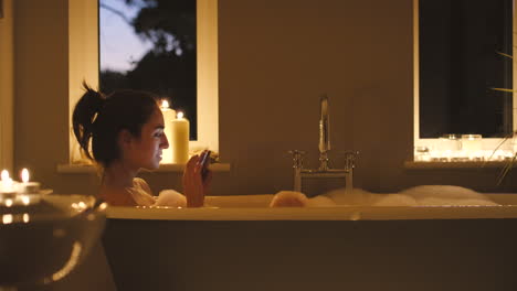 woman relaxing in a bubble bath with a phone