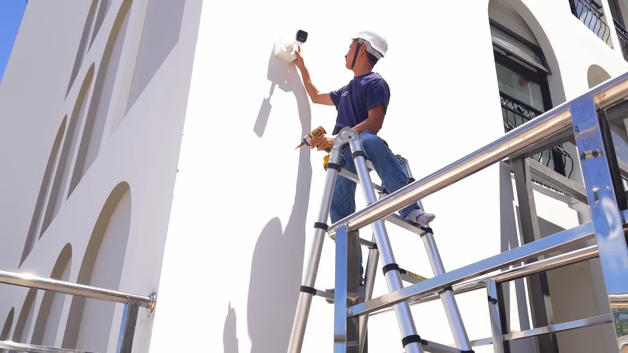 Technician installing a security camera on a building