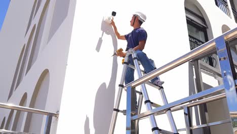 technician installing a security camera on a building