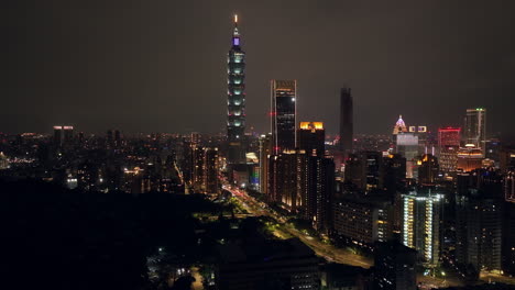 spectacular skyline of taipei at night with flashing lights of buildings - aerial wide shot