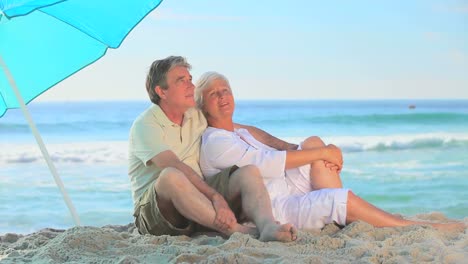 pareja madura sentada en una playa