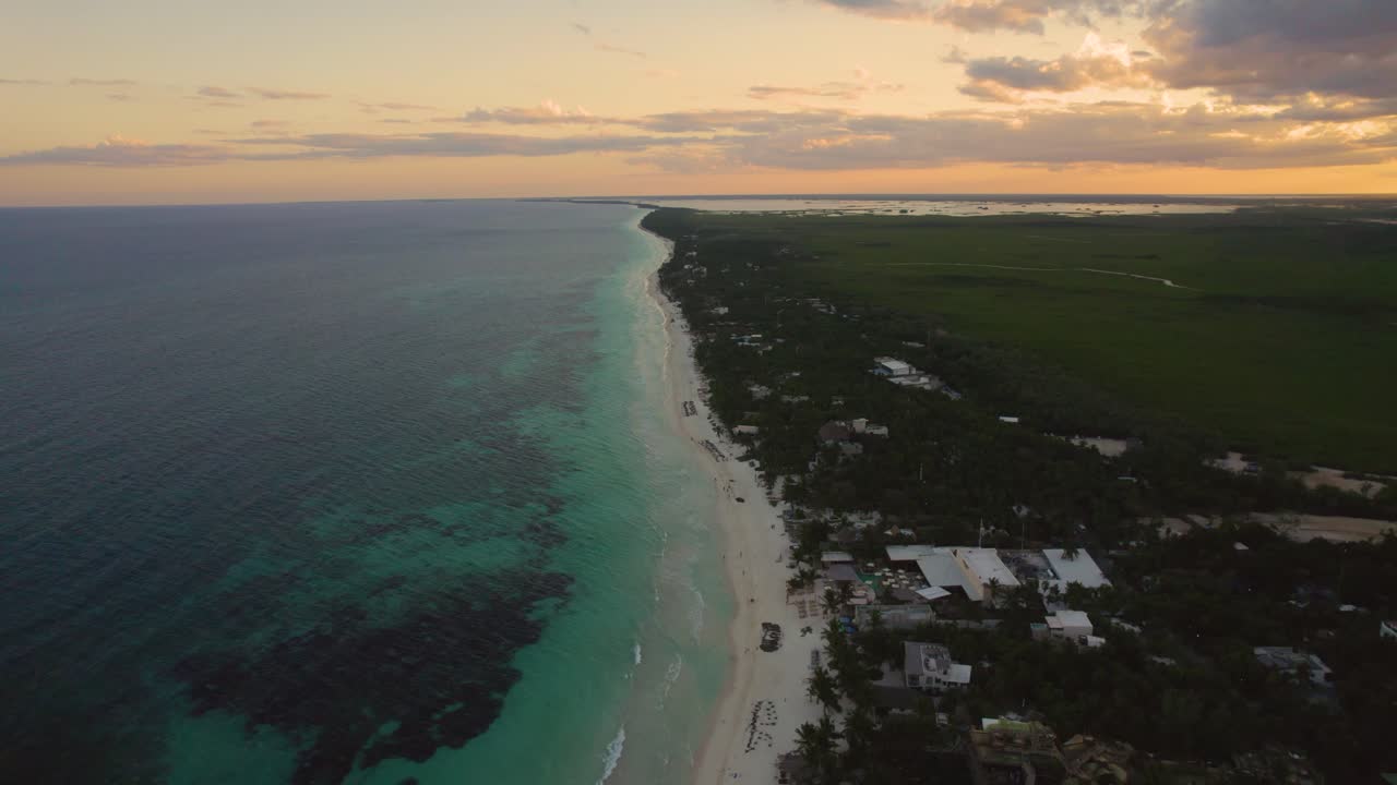 vista aérea de la playa de arena de akiin con olas turquesas del mar caribe y el cielo naranja de la puesta de sol en el horizonte
