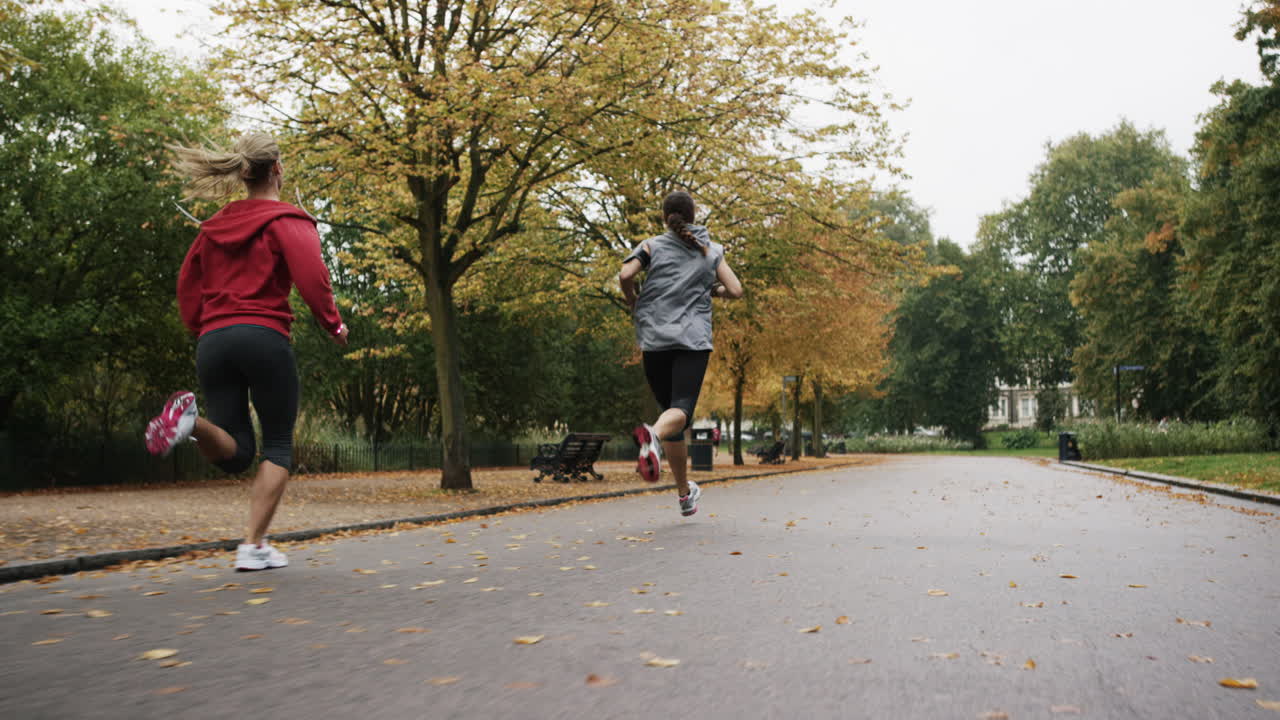 Gruppo di runner che corrono nel parco indossando tecnologia indossabile e dispositivi connessi.