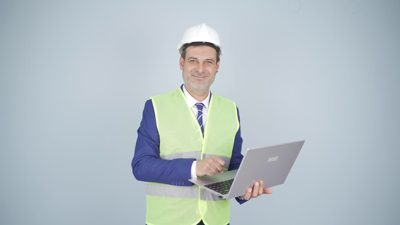 ingeniero con una computadora portátil riéndose de la cámara.