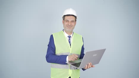 engineer holding laptop laughing at camera.