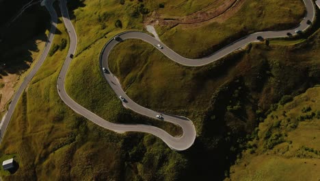 Aerial-view-of-a-italian-winding-road,-summer-trip,-transportation,-green-grass-and-coniferous,-color-graded