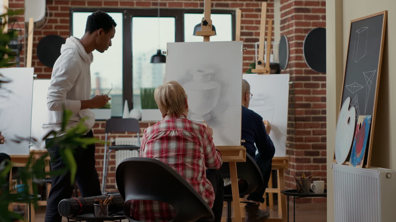 Male teacher giving advice to elder woman in drawing class
