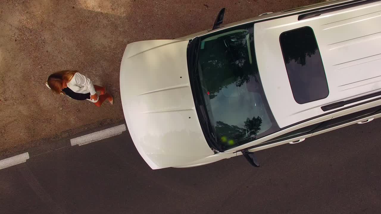 ripresa aerea 4k di una giovane donna incagliata che guarda sotto il cofano della sua auto in panne