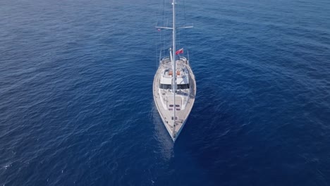 Arco-Aéreo-Disparado-Alrededor-De-Un-Yate-De-Vela-De-Ostras-Anclado-En-El-Océano-Azul