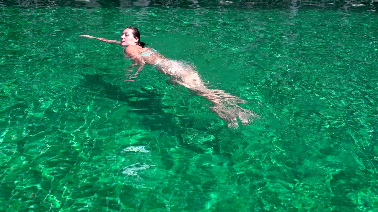 수영복 을 입은 여자 가 수영장 에서 목욕 을 하고 있다