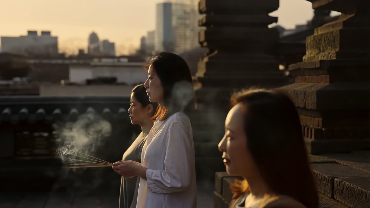 Women holding burning incense sticks during a spiritual ritual at sunset
