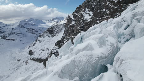 aerial close up view of the cracks of the face of a large glacier on a sunny day in winter in the alps