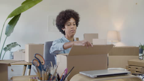 joven empresaria preparando paquete de cartón