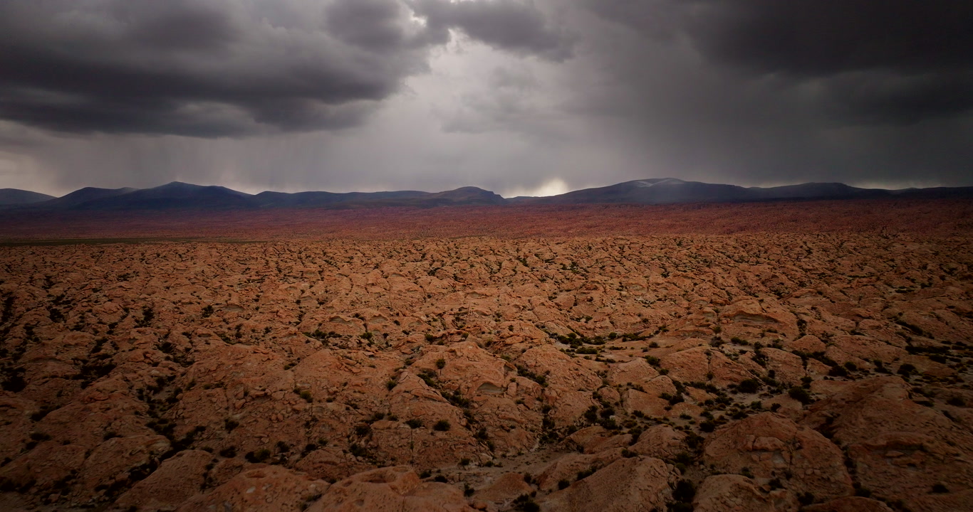 Otherworldly dry landscape of Siloli desert with dramatic storm clouds, aerial