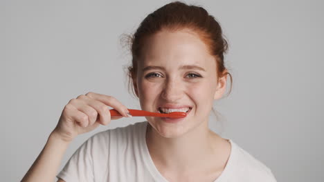 redheaded girl in front of camera on gray background.