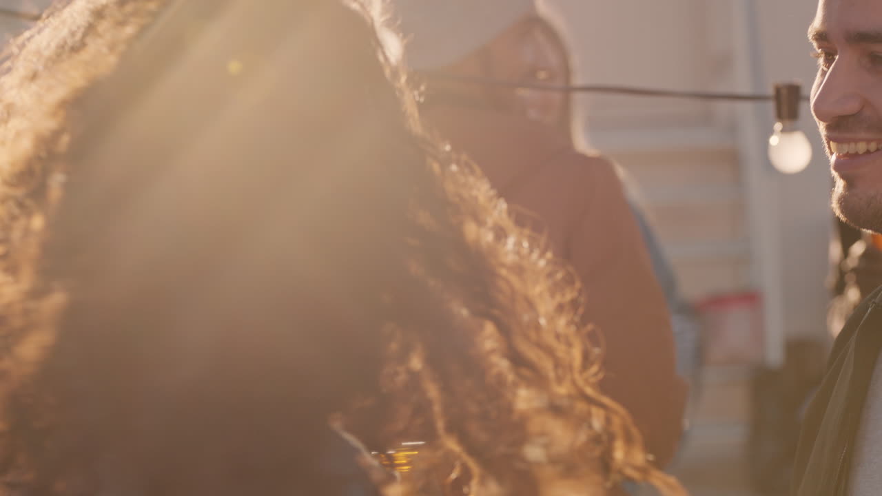 una joven pareja feliz disfrutando de una fiesta en la azotea bailando música animada compartiendo una relación romántica en una reunión social diversa al atardecer