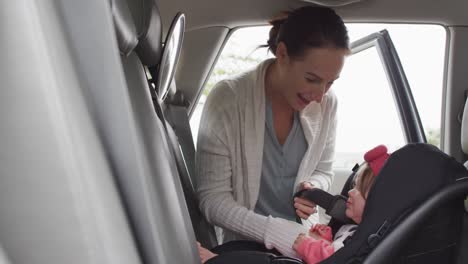 caucasian mother keeping her baby in safety seat in the car