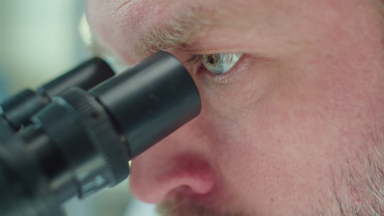 Experienced Scientist Looking through Microscope