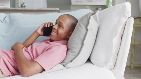 Video-of-happy-african-american-boy-using-smartphone-on-sofa