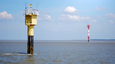 leading lights standing in the water in the wadden sea, with a blue sky and clouds. camera panning movement.