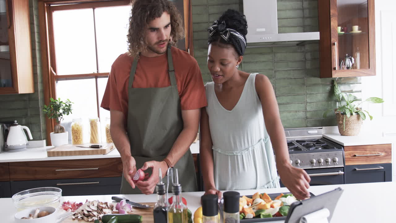 Young Caucasian man and African American woman prepare a meal together in a modern kitchen
