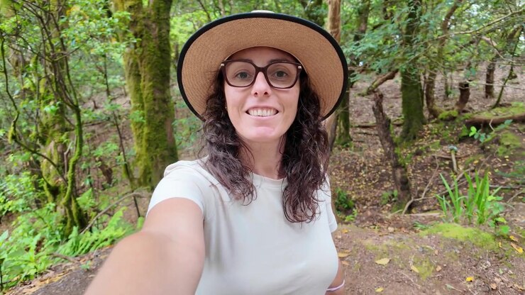 Giovane donna che registra un video selfie mentre fa escursioni in una foresta lussureggiante