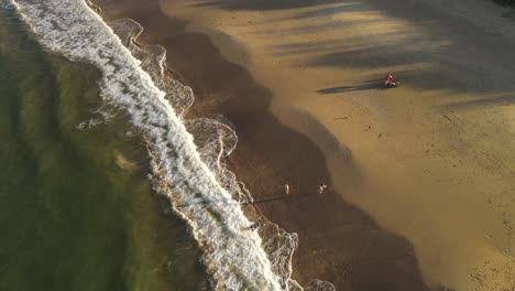toma de órbita aérea del día de la familia en la playa de arena con niños jugando durante la puesta de sol dorada - cámara lenta