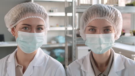 dos mujeres con abrigos de laboratorio y máscaras