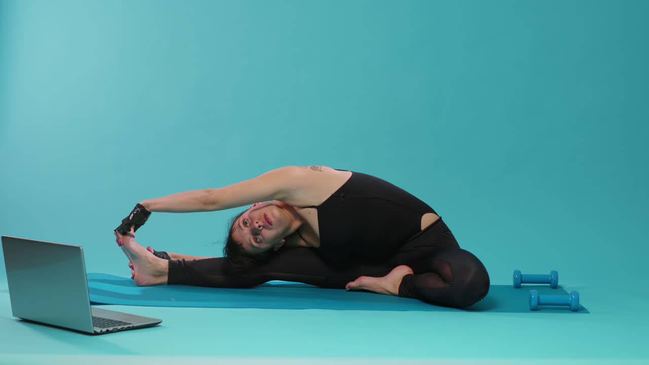 Athletic person stretching arms and legs muscles on yoga mat
