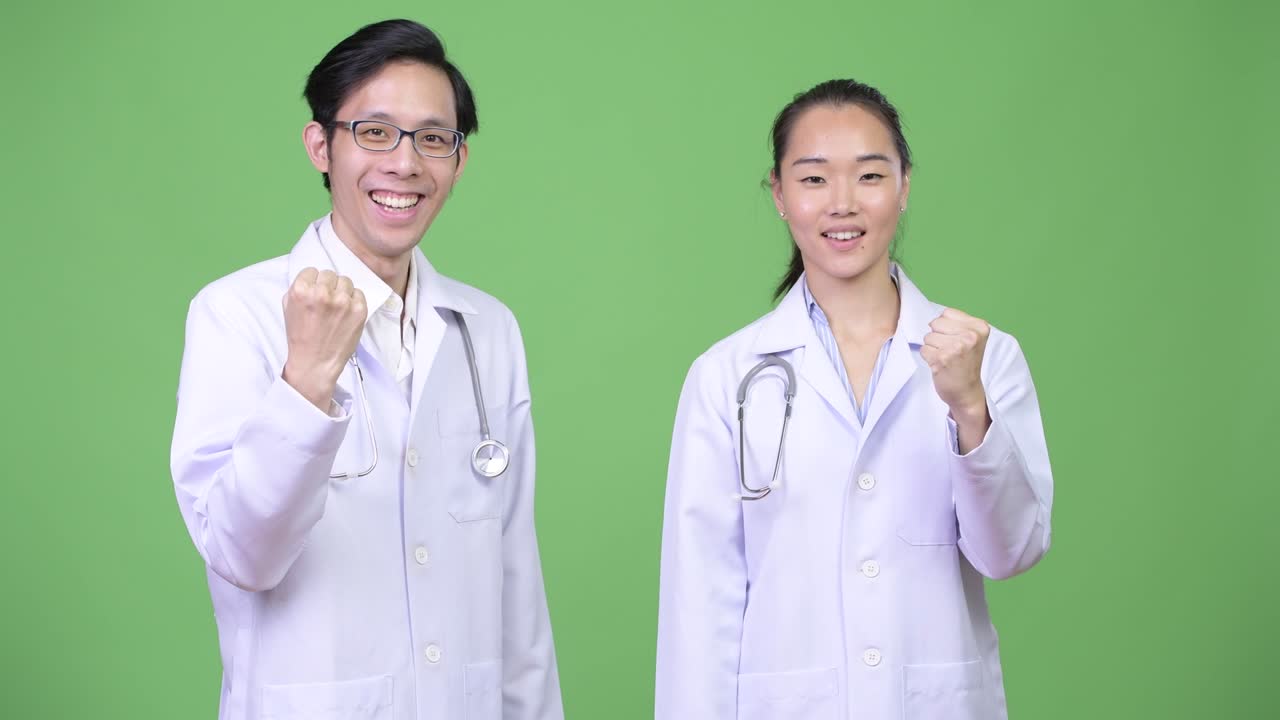Young Asian couple doctors with fist raised together