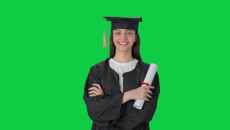 feliz chica graduada de la universidad india de pie con las manos cruzadas pantalla verde
