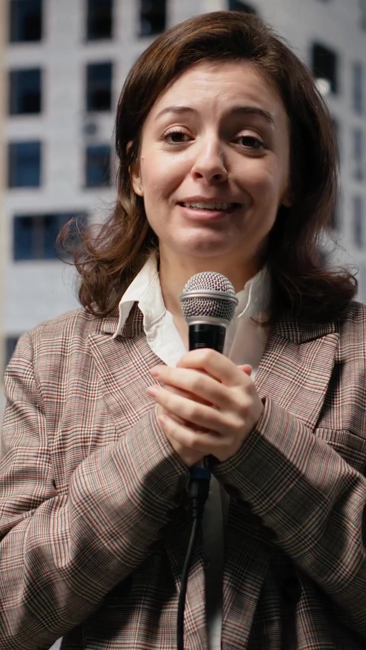 Video verticale: Reporter donna con microfono che si rivolge alla telecamera, presentando dalla strada