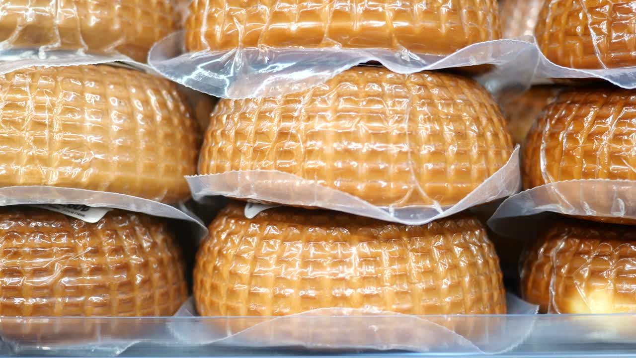Close up of a stack of wrapped cheese wheels in a grocery store
