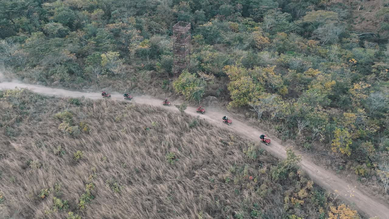 ATVs moving along a dirt trail surrounded by forest in Costa Rica, aerial view in 4K.