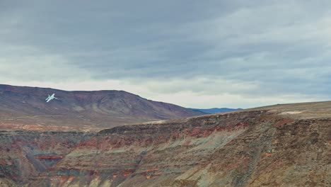 slow motion, close-up view of a fighter jet flying through a colorful canyon, leveling out from a right bank